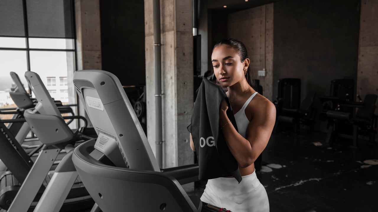 Female athlete using an OnlyGear microfiber towel on a treadmill — Demonstrating the towel's absorbency and functionality during workouts.